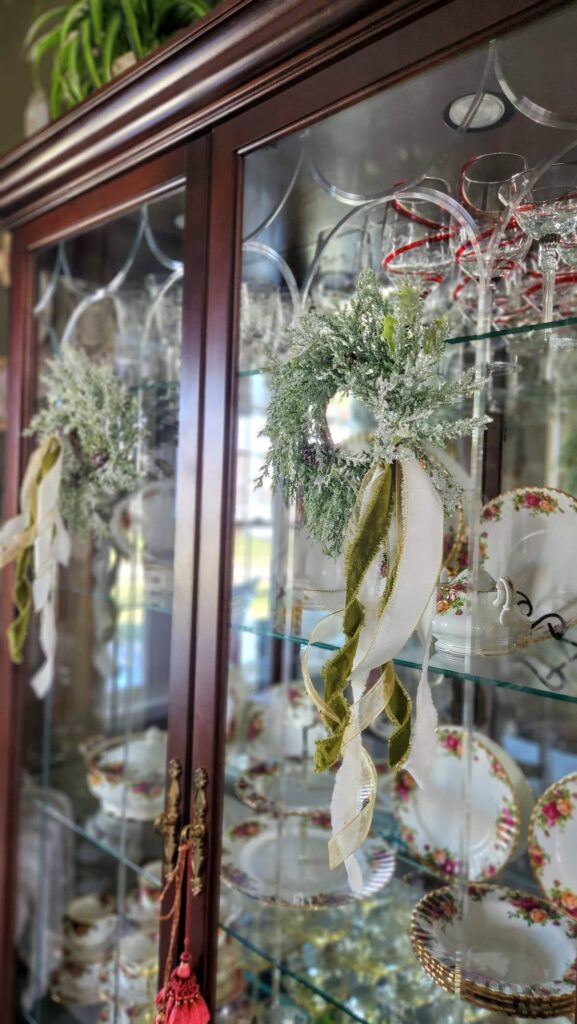 two cabinet door with glass and wreaths hanging on them