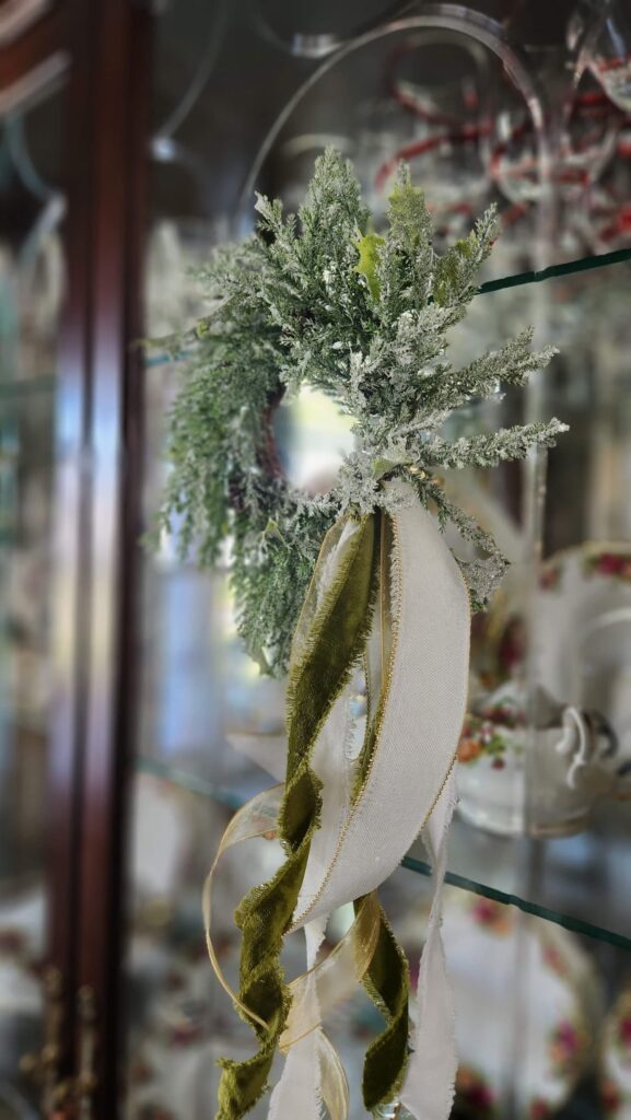 christmas wreath hanging on a glass china cabinet door