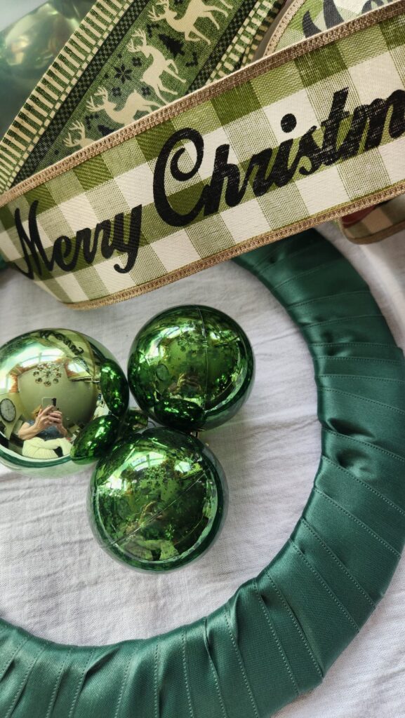 plaid ribbon in green with merry christmas written on it and green ornament bulbs