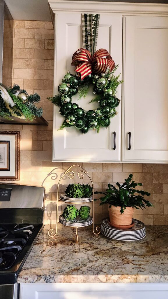 green ornament wreath with red ribbon hanging on kitchen cupboard