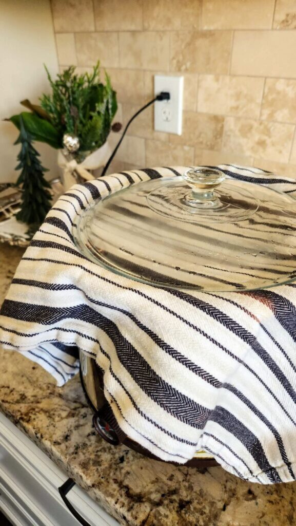 black and white dish cloth covering crock pot with lid on it