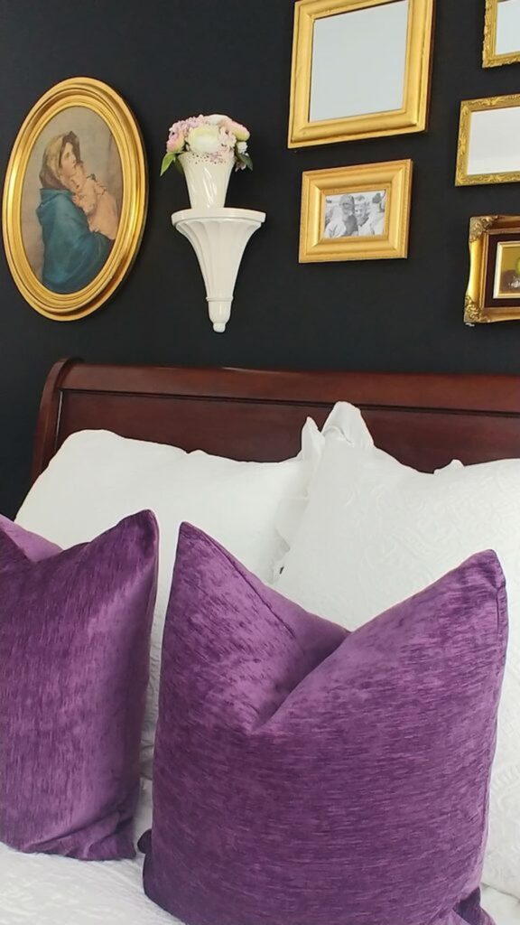 black accent wall in bedroom with gold frames on wall