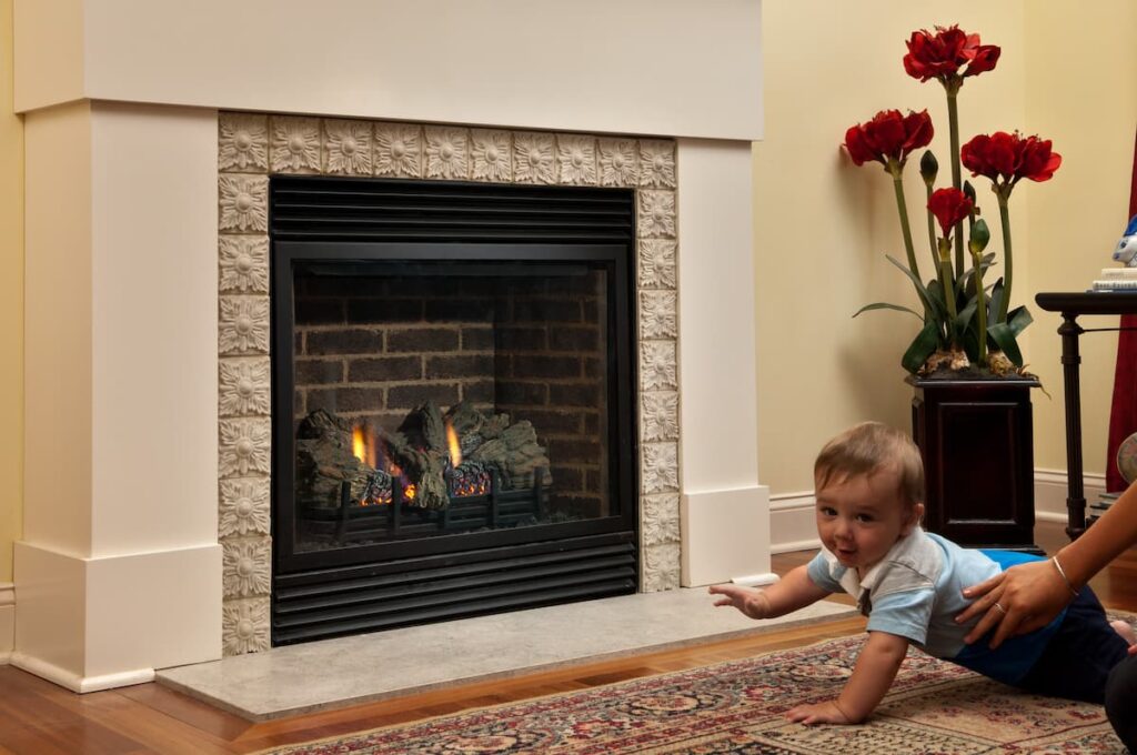child by fireplace with a safety screen on the gas fireplace