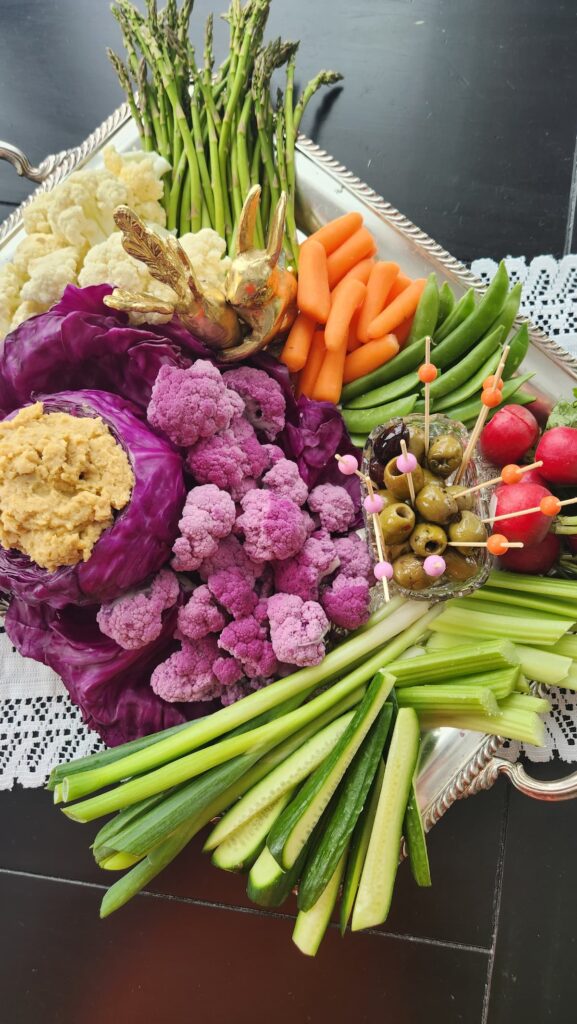 overhead photo of silver tray with colorful veggies on it carrots, purple cauliflower, red radishes, asparagus and olives