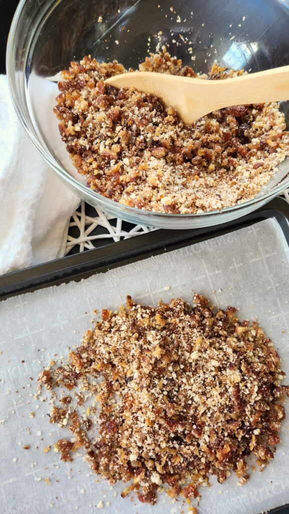 glass bowl of flax seed mixture being added to a baking sheet