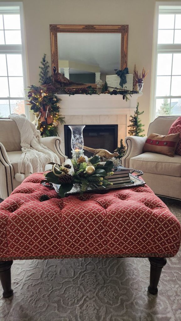 living room view with fireplace and white chairs in front of mantel and red pattern ottoman decorated for Christmas time
