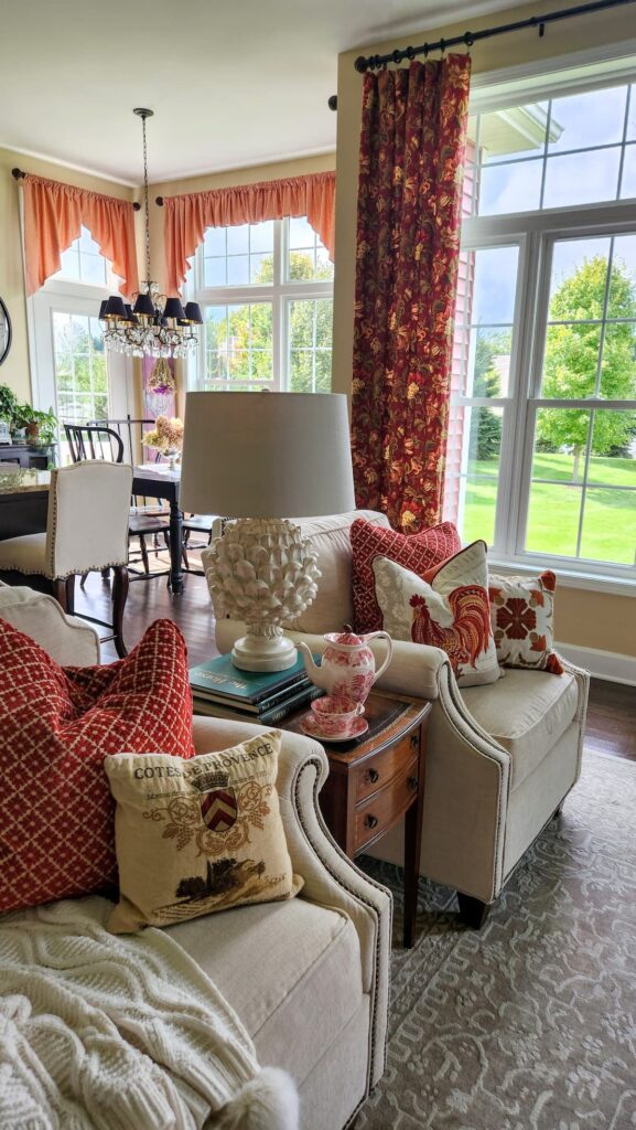 living room with white chairs and brick red home decor and drapes