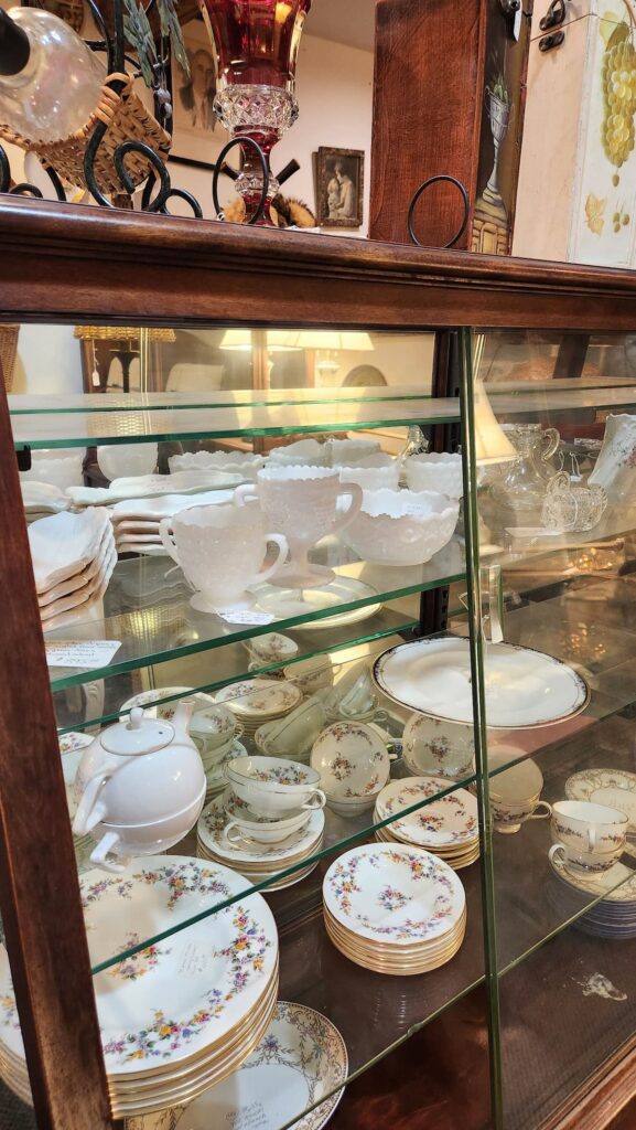 old glass cabinet with vintage dishes in a thrift shop