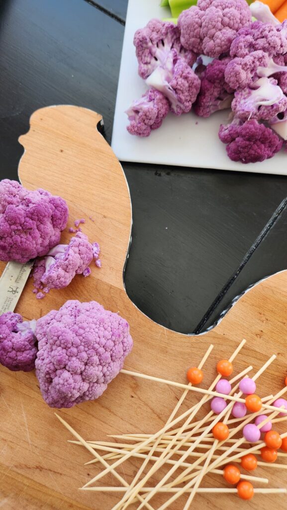 wooden cutting board in shape of a rooster with purple cauliflower on top