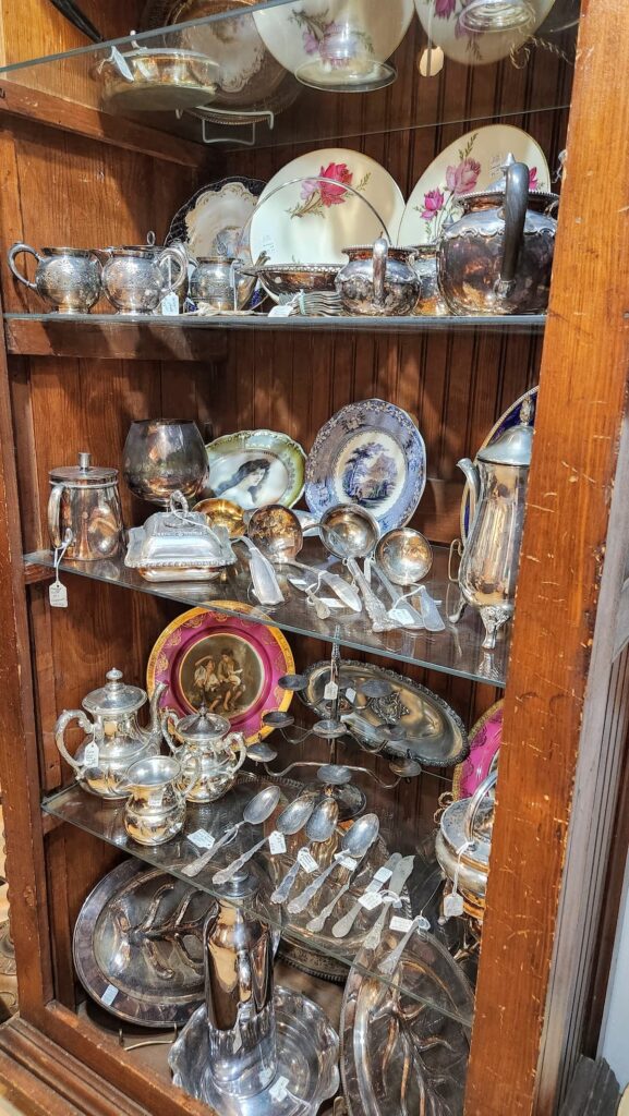 old wooden cabinet with shelves filled with silver pieces, dishes