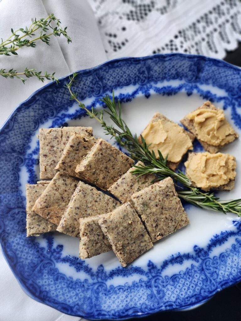 easy gluten free crispbread squares on a blue antique dish with a sprig of rosemary on dish