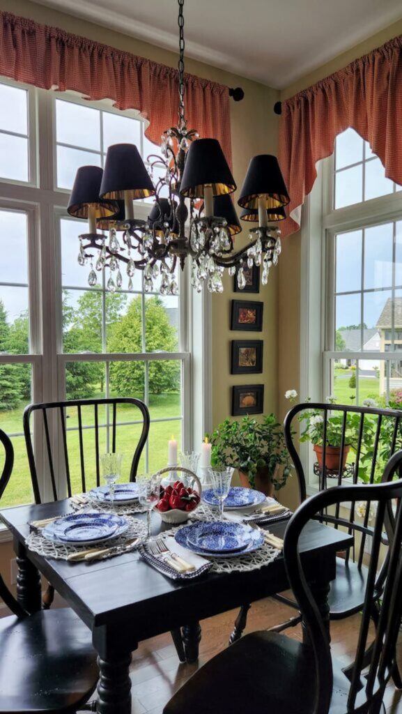 blue and white dishes on black table in breakfast room next to a window
