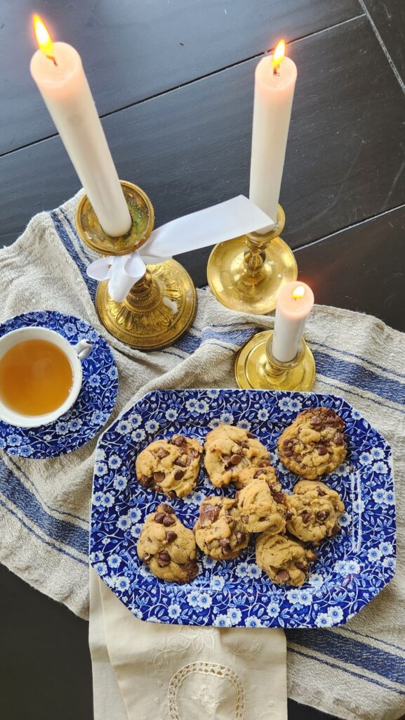 cookies on blue and white dish with candles and a cup of tea