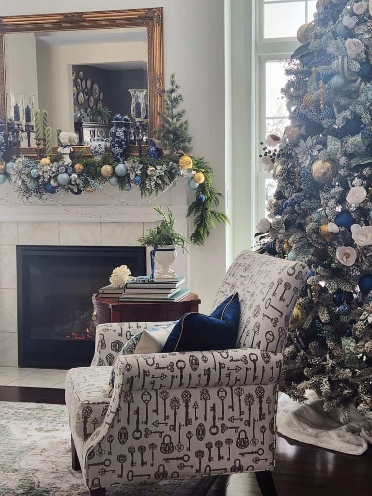 Christmas mantle with blue and white Christmas ornaments and tree on side in front of fireplace