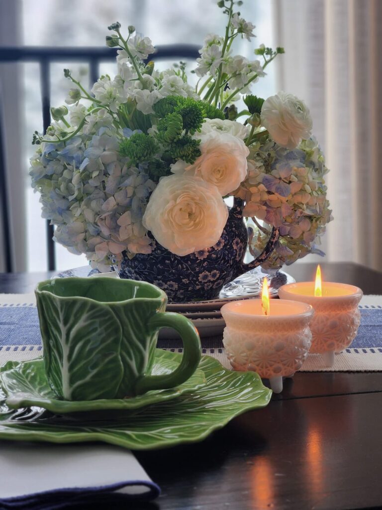 vintage teapot filled with fresh florals, candles and cabbage ware tea cup on table