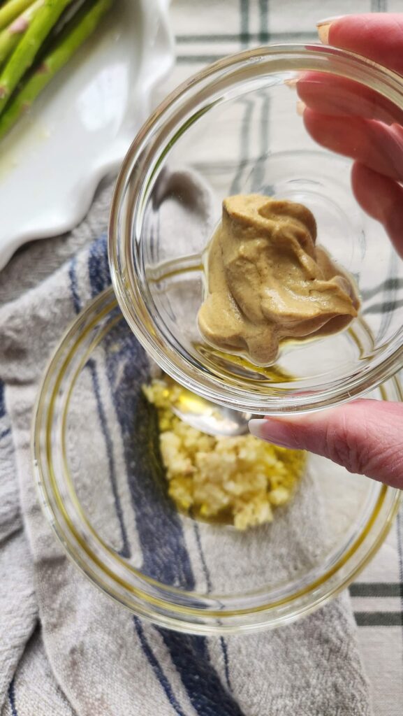 measuring dijon mustard for baked salmon marinade in small bowl
