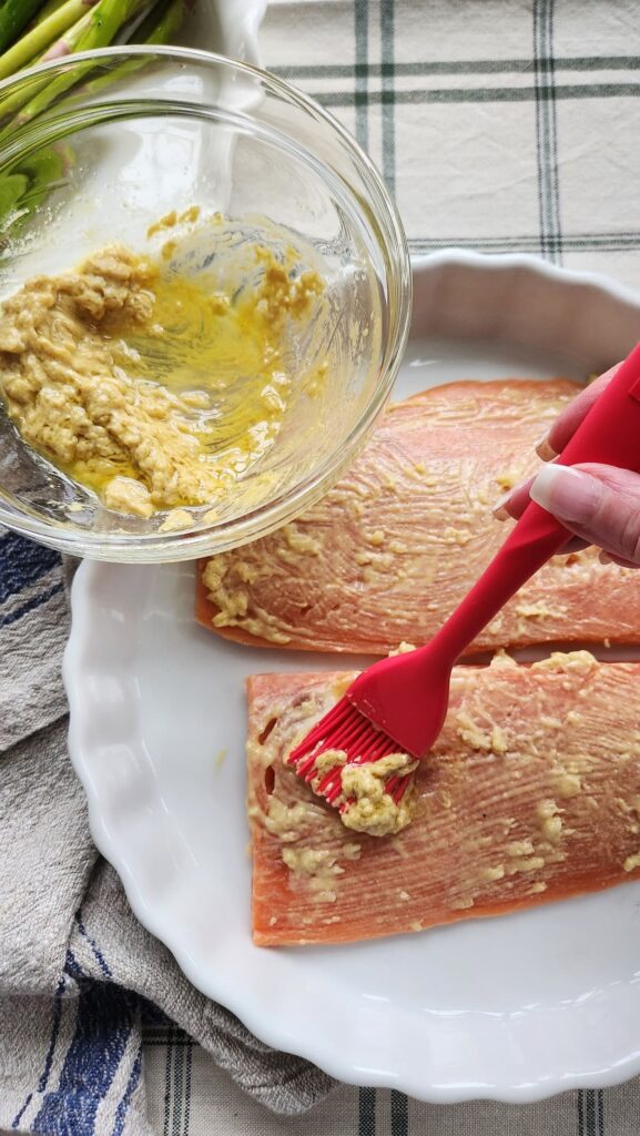 brushing dijon herb marinade onto fresh salmon fillets"