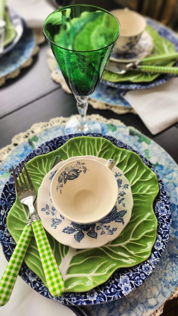 vintage green goblet with dish stack of mismatched dishes