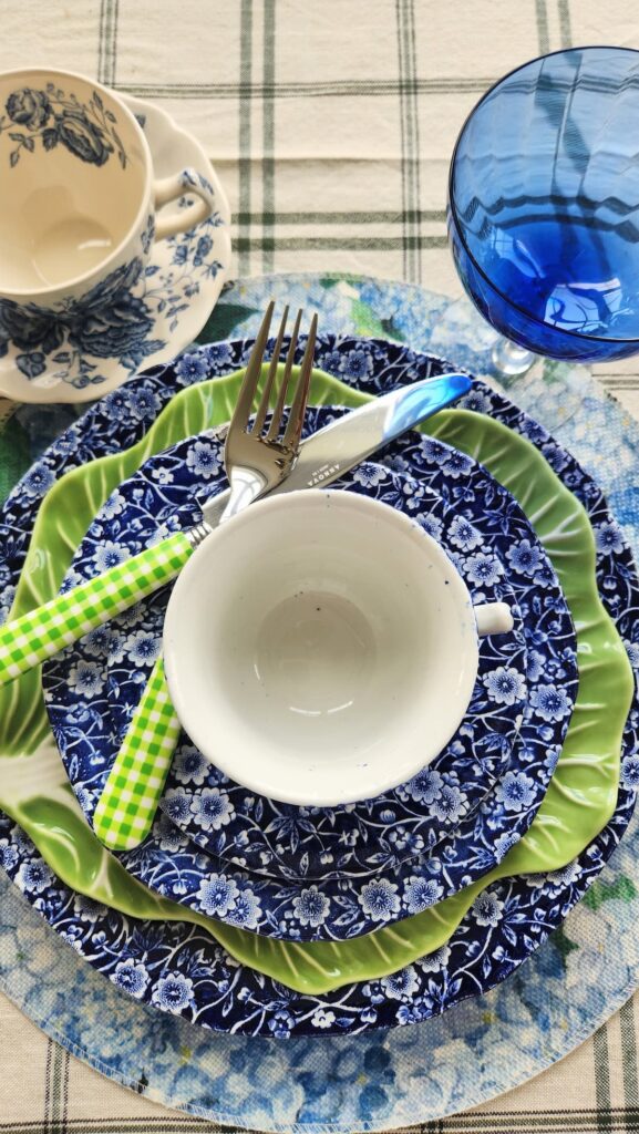 hydrangea placemat with blue chintz dishes, cabbageware dish and teacup stacked