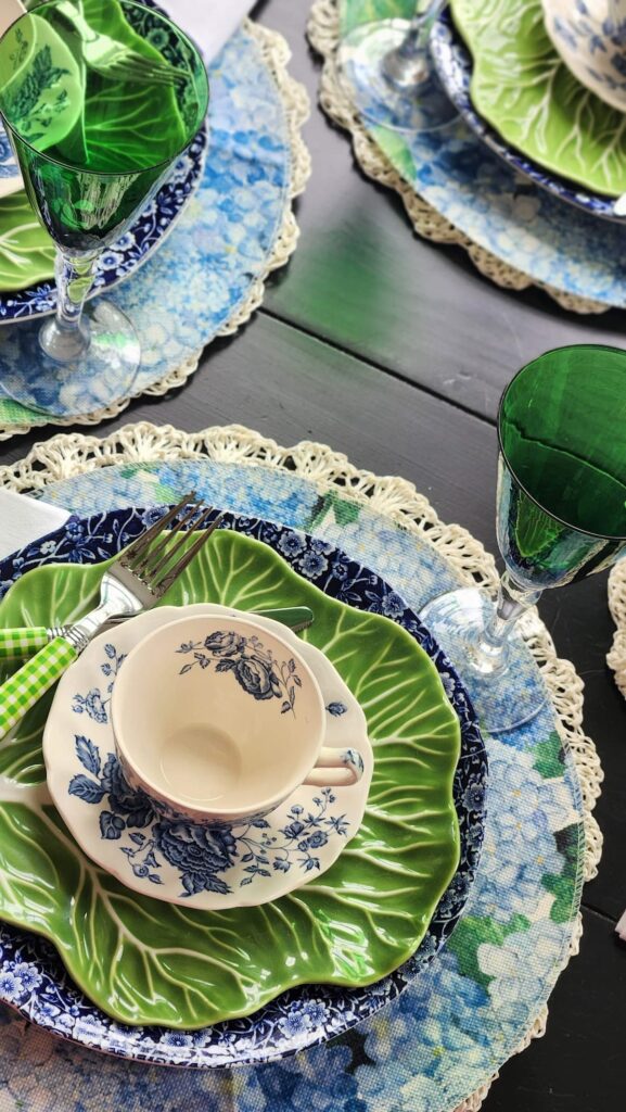 dish settings with chintz dishes, green goblets on table