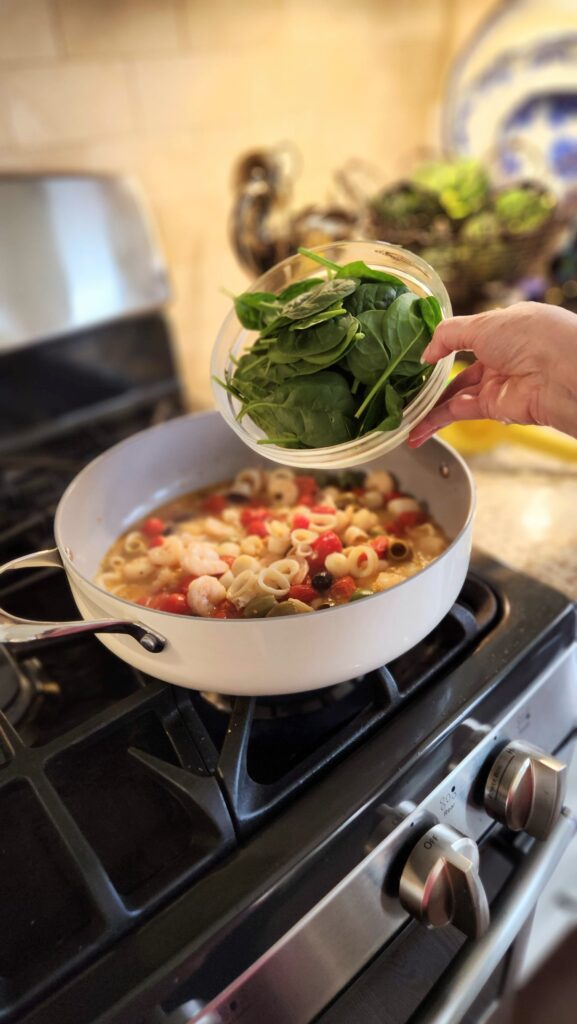 adding fresh baby spinach to trader joes seafood blend skillet recipe