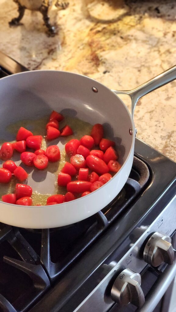 cherry tomatoes blistering in white skillet for mediterranean seafood recipe