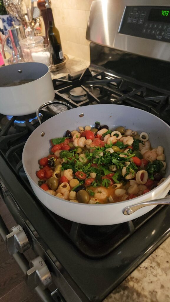 finished trader joes seafood blend skillet with fresh parsley on gas stove