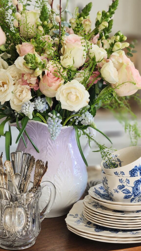 How to arrange spring flowers in a vintage vase breakfast room tray blue and white china teacups stacked silver spoons crystal holder pink roses lavender pitcher