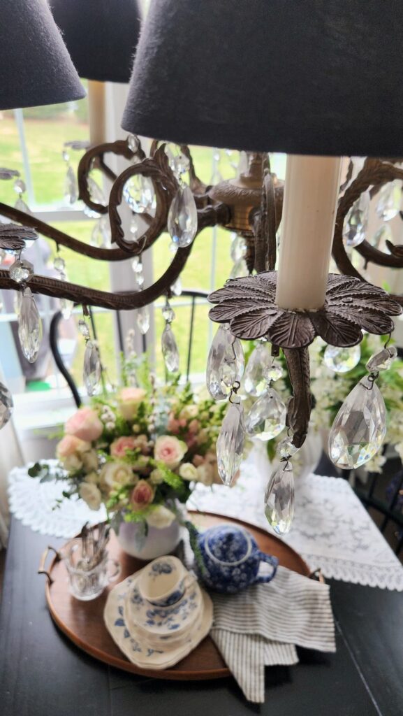 Crystal chandelier close detail spring flower arrangement vintage vase breakfast room pink roses blue and white china tray below French country decor