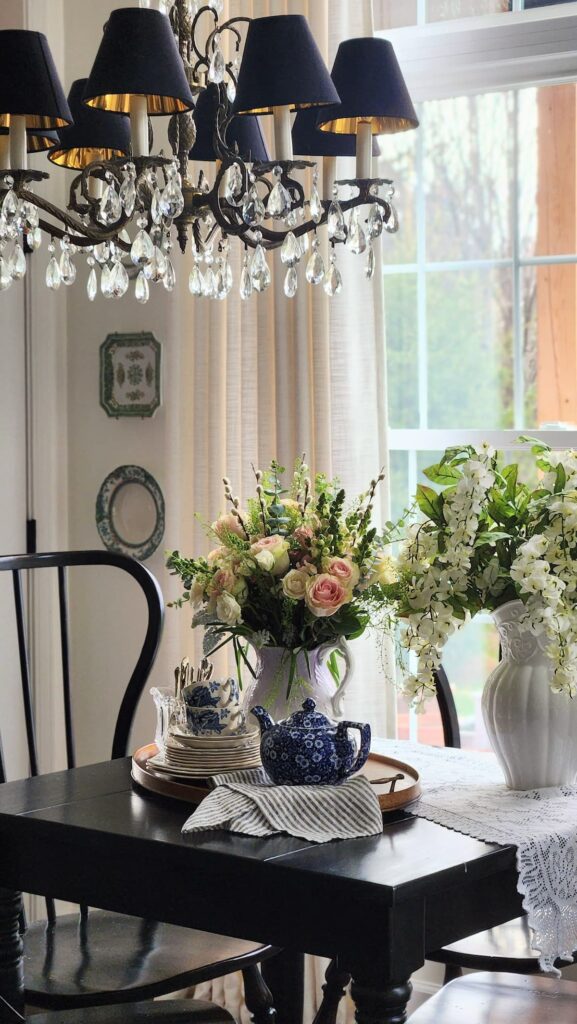 How to arrange spring flowers in a vintage vase breakfast room full view crystal chandelier black chairs pink roses white wisteria vintage pitcher