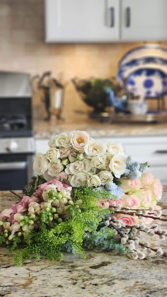 How to arrange spring flowers in a vintage vase step one first pink roses placed lavender pitcher flowers laid out counter beginning arrangement