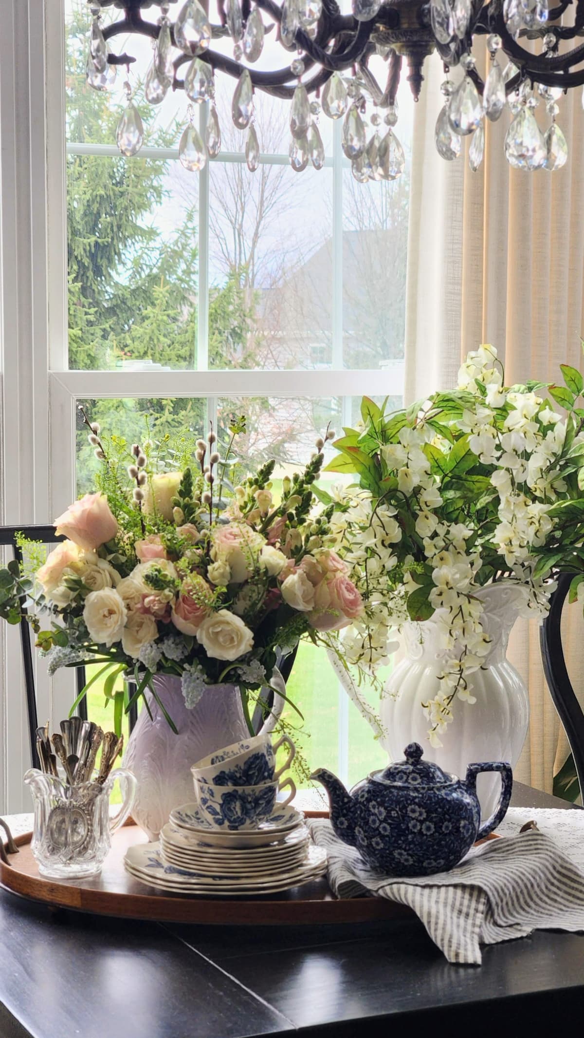 How to arrange spring flowers in a vintage vase breakfast room two arrangements pink roses lavender pitcher white wisteria white pitcher crystal chandelier French country decor