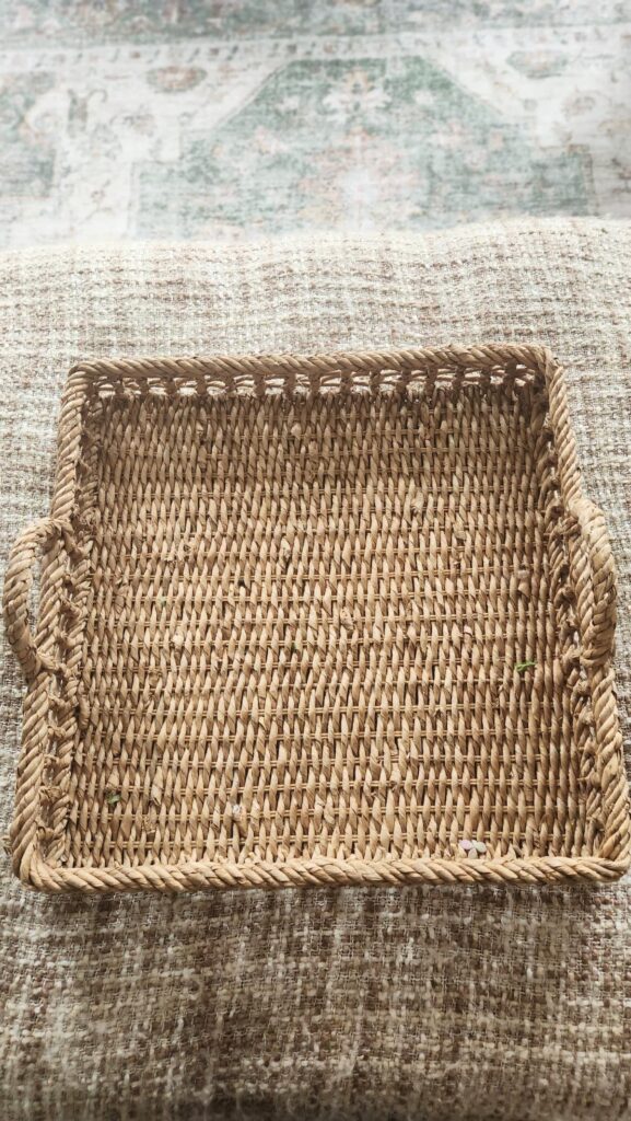 Empty large wicker tray with rope handles on ottoman living room French country home decor