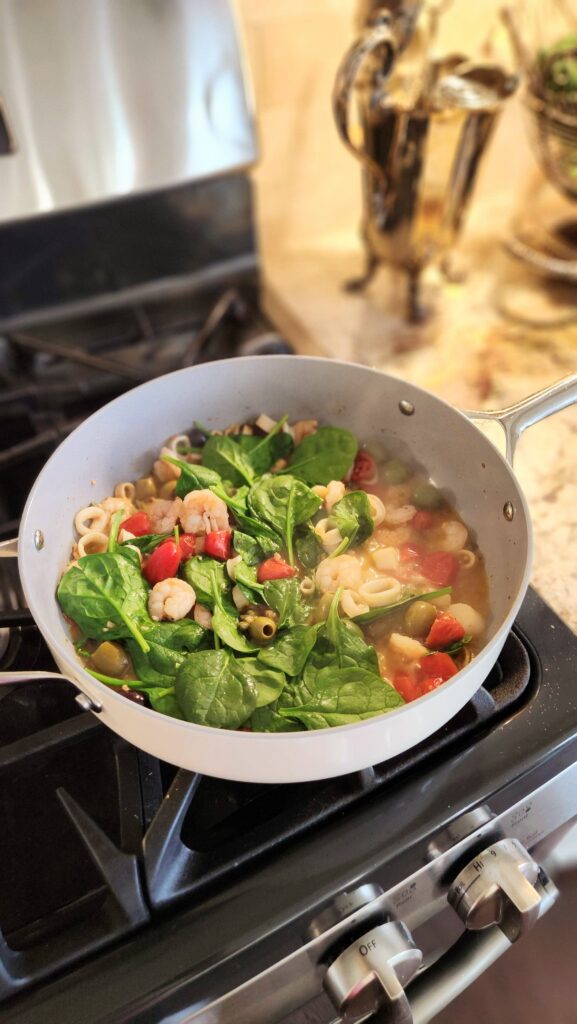 spinach wilted into easy trader joes seafood skillet with tomatoes and olives