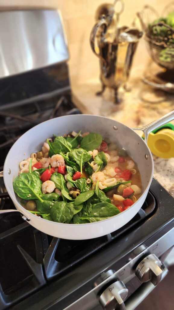 fresh spinach wilting into one pan mediterranean seafood skillet dinner