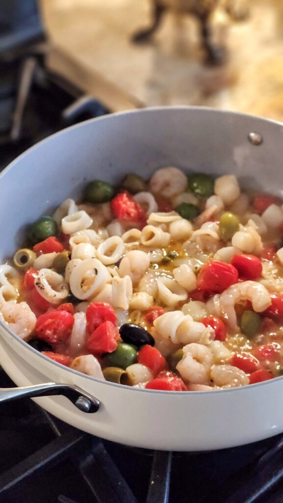 trader joes seafood blend nestled into mediterranean tomato olive skillet