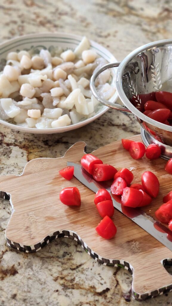 trader joes seafood blend and halved cherry tomatoes on cutting board