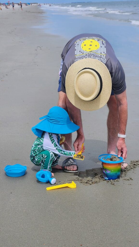 baby and grandpa on the beach building a castle in the sand