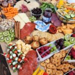 Large charcuterie grazing board with cured meats cheese fresh fruit crackers and vegetables for a crowd