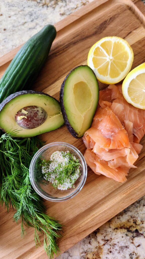 easy smoked salmon cucumber bites ingredients avocado lemon fresh dill and herb salt on cutting board