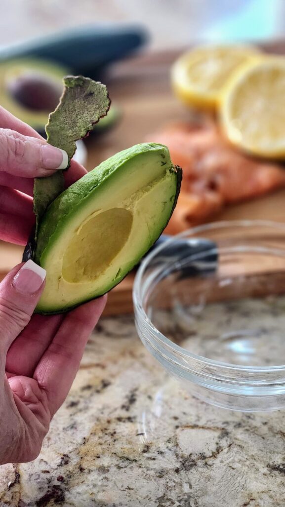 peeling ripe avocado to make avocado mash for smoked salmon cucumber bites