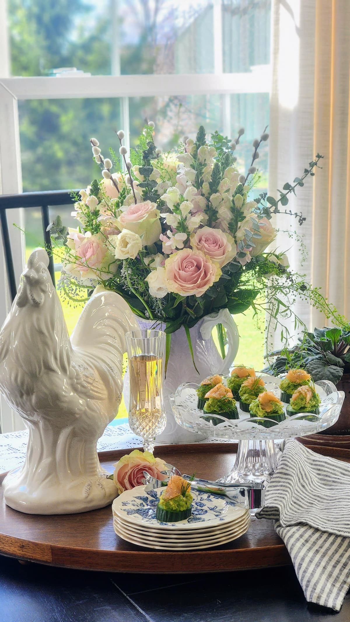 smoked salmon cucumber bites party appetizer styled with pink roses and white rooster on spring table