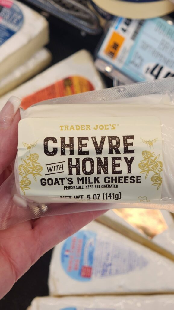 Trader Joes chevre with honey goats milk cheese held in hand for charcuterie board