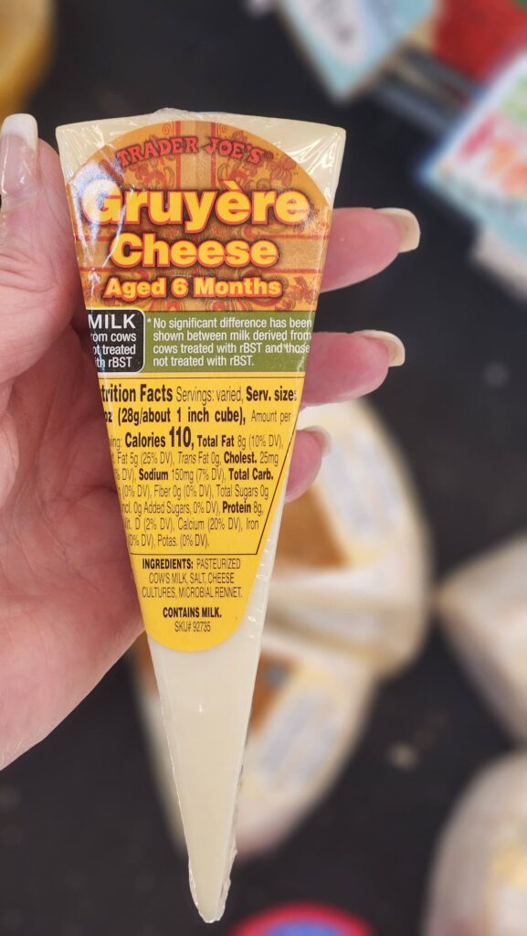 Trader Joes Gruyere cheese aged six months held in hand for charcuterie board