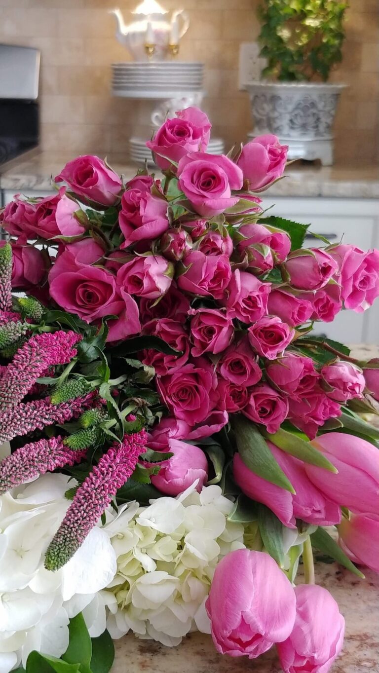 Pink spray roses tulips and white hydrangea from Trader Joes on kitchen counter with white teapot and dishes in background