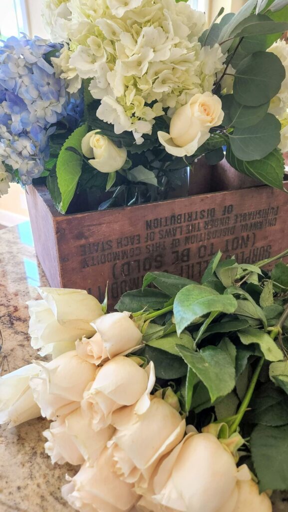 White roses and blue and white hydrangea arranged in vintage wooden crate from Trader Joes flowers